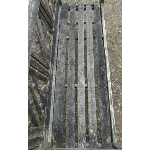 155 - A weathered three seat garden bench with slatted seat and lattice panelled back beneath a shaped rai... 