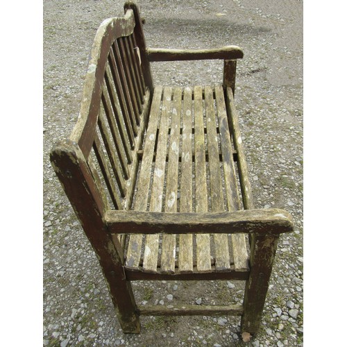 111 - A weathered and stained teak garden bench with slatted seat and back beneath an arched rail, 120 cm,... 