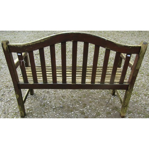 111 - A weathered and stained teak garden bench with slatted seat and back beneath an arched rail, 120 cm,... 