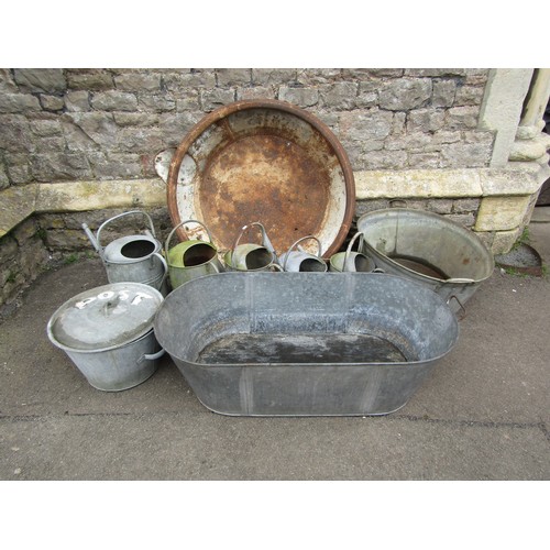 A quantity of galvanised items to include two oval baths, two handled pan and cover, watering cans, and a large weathered tin shallow dairy pan (af capable of hanging) 3ft diameter approx