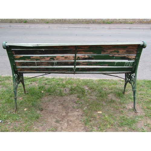 279 - A two seat garden bench with painted wooden slatted seat raised on decorative pierced cast iron end ... 