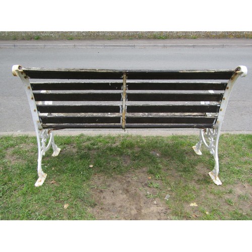 282 - A two seat garden bench with slatted seat and combined back raised on painted cast iron scroll patte... 