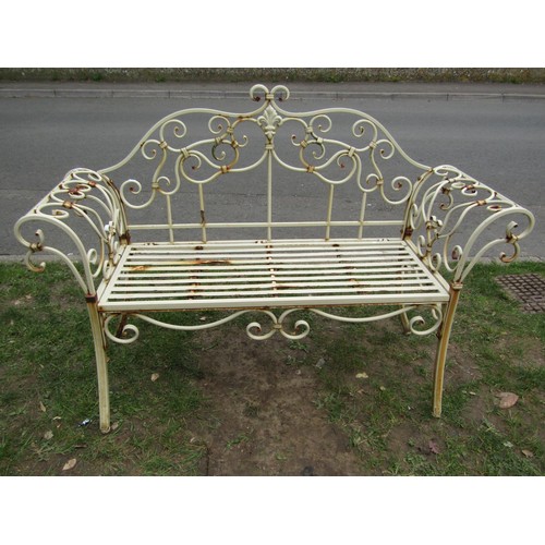 A weathered cream painted two seat metal bench loosely in the Regency style with shaped outline and open scrolled detail, strapwork seat and swept supports, 143 cm wide