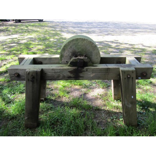 192 - A carved natural stone grinding wheel, 45cm diameter, set in a substantial weathered pine stand