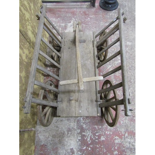 530 - An antique wooden hand cart with open slatted sides and four spoke wheels with iron rims