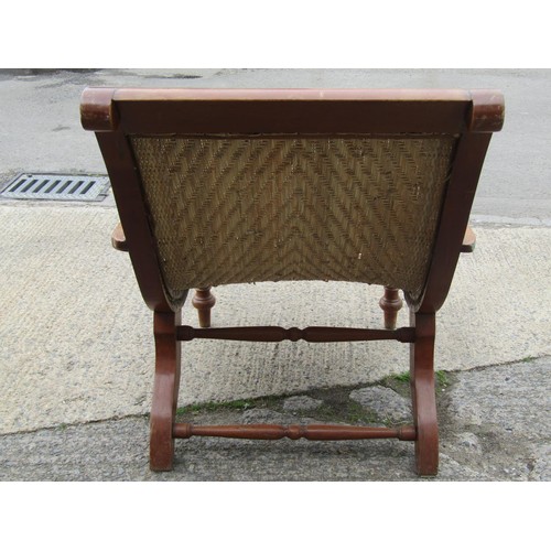 543 - An early 20th century teak plantation chair, with curved woven rattan seat and folding / extending a... 