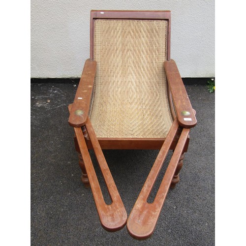 543 - An early 20th century teak plantation chair, with curved woven rattan seat and folding / extending a... 