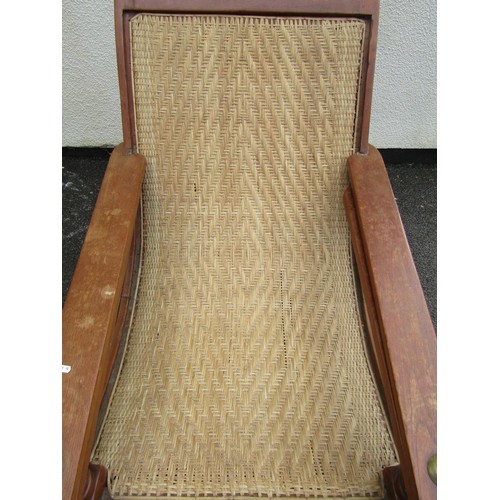 543 - An early 20th century teak plantation chair, with curved woven rattan seat and folding / extending a... 