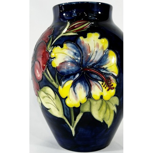 38 - A Moorcroft Hibiscus pattern vase upon a  blue ground, 17 cm