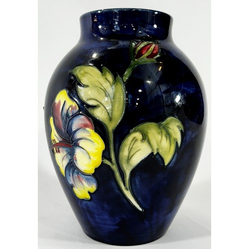 38 - A Moorcroft Hibiscus pattern vase upon a  blue ground, 17 cm