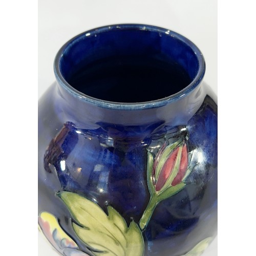 38 - A Moorcroft Hibiscus pattern vase upon a  blue ground, 17 cm