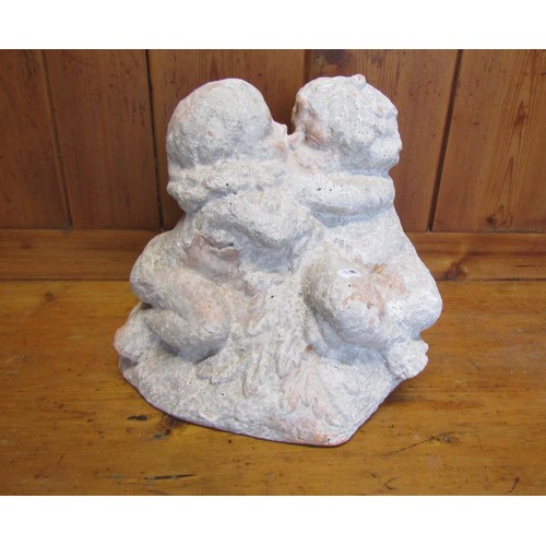 1019 - A faux weathered terracotta garden ornament in the form of kissing cherubs, 26 cm high
