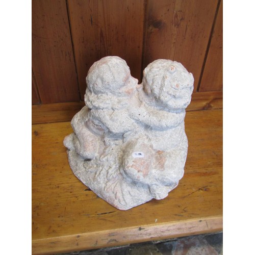 1019 - A faux weathered terracotta garden ornament in the form of kissing cherubs, 26 cm high