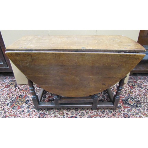 1141 - An 18th century oak and fruitwood gateleg table enclosing a single frieze drawer on turned supports,... 