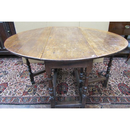 1141 - An 18th century oak and fruitwood gateleg table enclosing a single frieze drawer on turned supports,... 