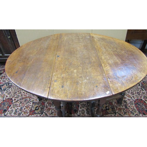 1141 - An 18th century oak and fruitwood gateleg table enclosing a single frieze drawer on turned supports,... 