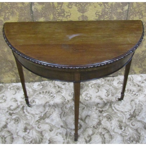 1210 - An Edwardian mahogany demi-lune fold over top card table in the Georgian style raised on square tape... 