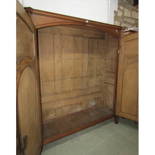 1262 - A low oak hanging hall wardrobe enclosed  by a pair of carved and panelled doors, within a panelled ... 