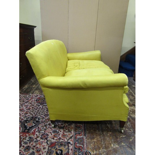 1328 - A Howard & Son two seat sofa with scrolled arms raised on square taper legs with brass cup castors, ... 