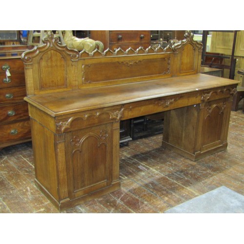 1378 - A Victorian oak sideboard with heavy Gothic influence, the base enclosed by two cupboards and three ... 