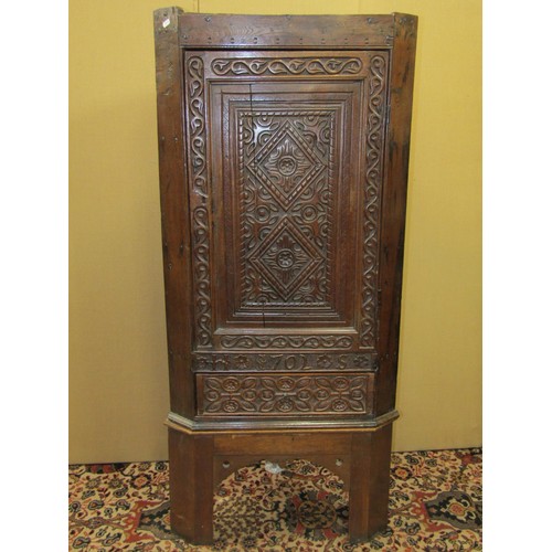 1414 - An early oak hanging corner cupboard, the carved face with geometric detail, and dated 1702, set on ... 