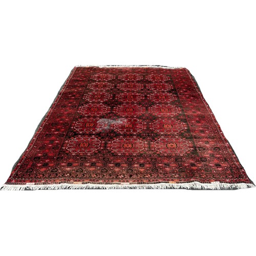 1514 - A large Afghan wool rug with a central panel design on a predominantly red ground,285 x 205cm approx... 