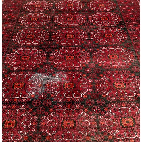 1514 - A large Afghan wool rug with a central panel design on a predominantly red ground,285 x 205cm approx... 