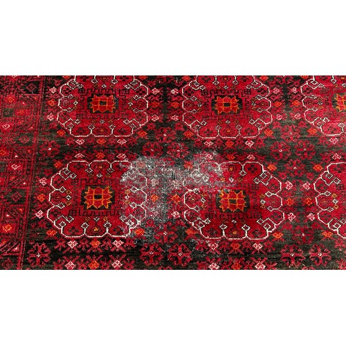 1514 - A large Afghan wool rug with a central panel design on a predominantly red ground,285 x 205cm approx... 