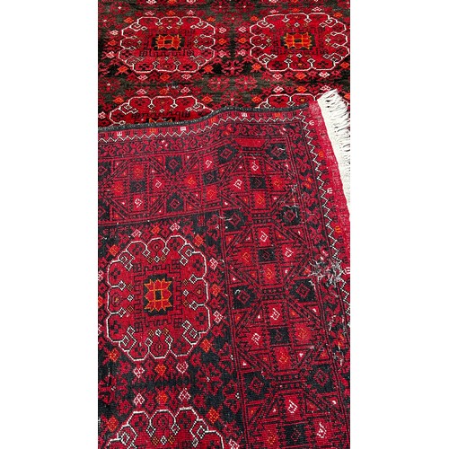 1514 - A large Afghan wool rug with a central panel design on a predominantly red ground,285 x 205cm approx... 