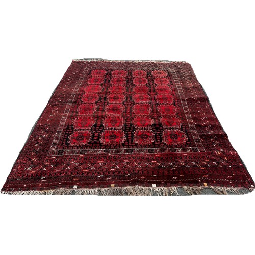 1518 - An Afghan carpet with a red and black panelled design, 260 x 200cm approximately