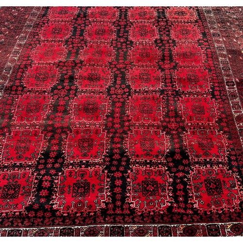 1518 - An Afghan carpet with a red and black panelled design, 260 x 200cm approximately