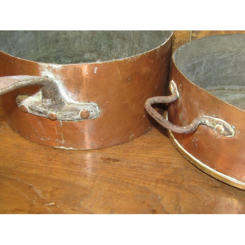 1072 - Three 19th century copper saucepans with heavy iron handles, average diameter 35cm