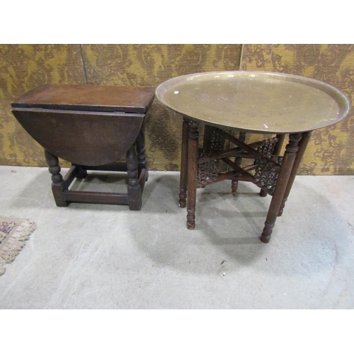 1083 - An old English oak drop leaf occasional table together with an Indian brass tray top table with fold... 