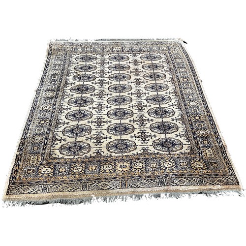 1520 - A Bokara style carpet, with three row of elephant foot blue guls on a beige ground, 185 x 130cm appr... 