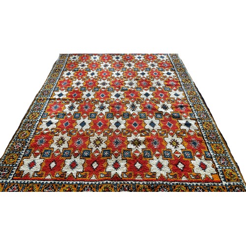 1506 - A Moroccan wool carpet with cream stars on a predominantly orange ground, 280 x 190cm approximately.