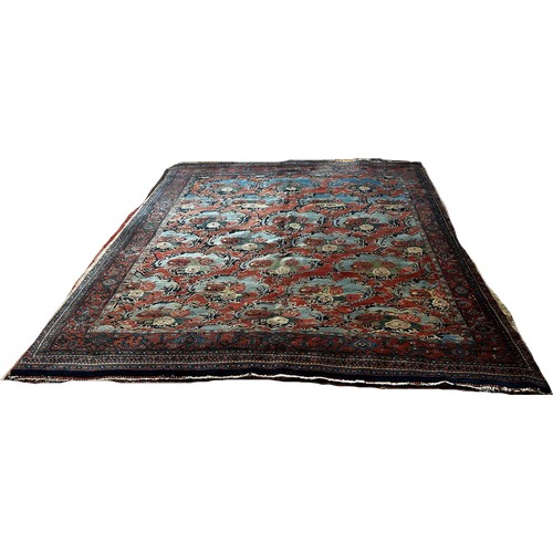 1512 - An Old Persian carpet with a repeating floral pattern on a pink ground, one corner badly worn with m... 