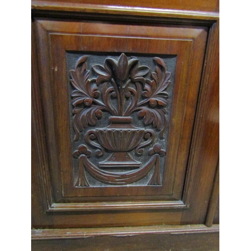 1264 - An Edwardian library bookcase in walnut, the base enclosed by a pair carved and panelled doors and t... 