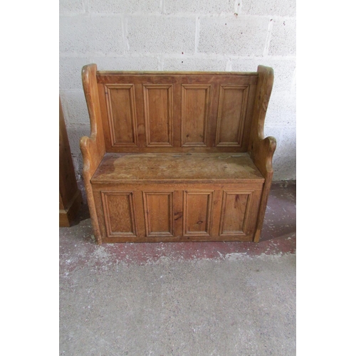 1445 - A stripped and waxed pine settle with rising lid, the panelled back within a shaped outline, 93cm wi... 