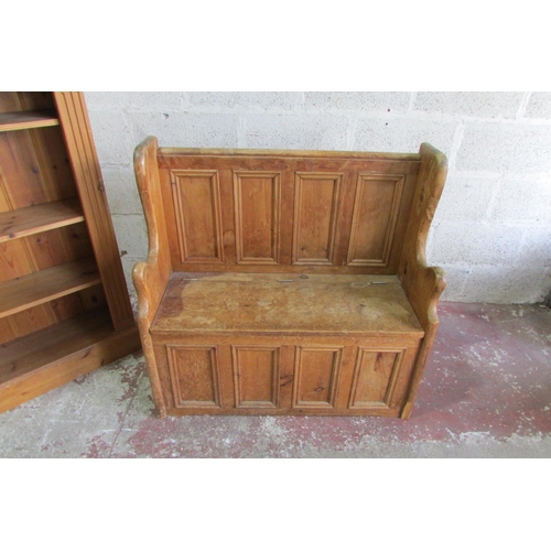 1445 - A stripped and waxed pine settle with rising lid, the panelled back within a shaped outline, 93cm wi... 