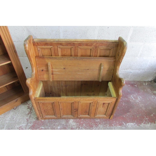 1445 - A stripped and waxed pine settle with rising lid, the panelled back within a shaped outline, 93cm wi... 