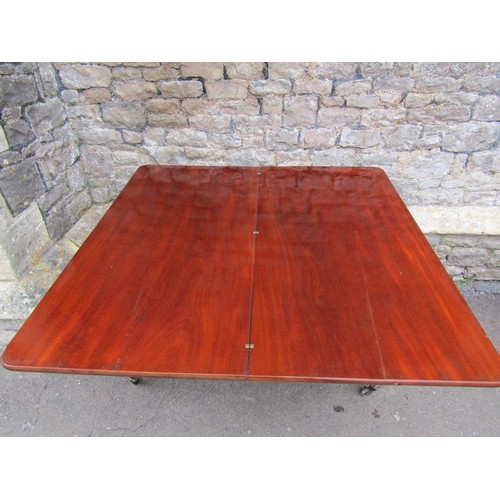 1402 - A 19th century mahogany mahogany fold over top dining table raised on four octagonal supports and ca... 