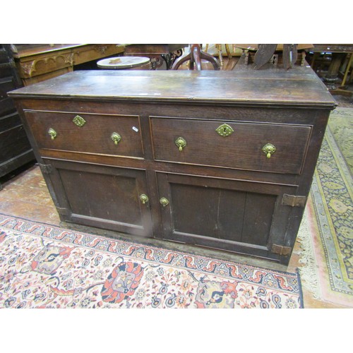 1413 - A Georgian oak dresser base with two frieze drawers and two panelled doors, with iron butterfly hing... 