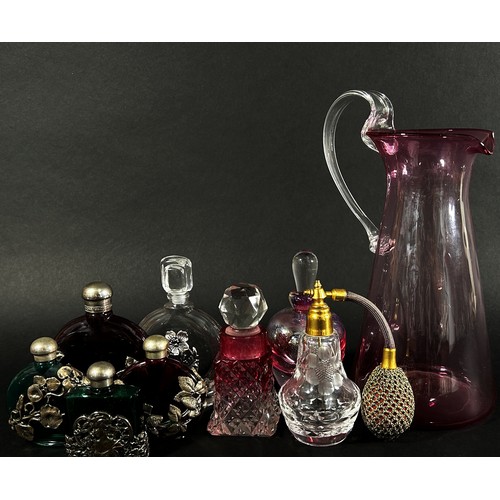 157 - A collection of glass scent bottles, some with silver metal floral swags and four silver topped jars... 