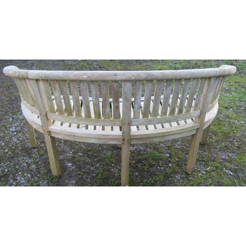 1003 - A weathered silvered teak banana shaped garden bench  160 cm wide