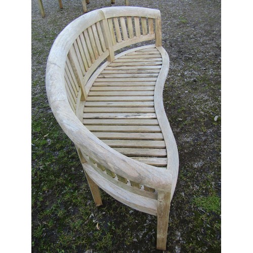 1002 - A weathered silvered teak banana shaped garden bench  158 cm wide (complete with seat cushion)