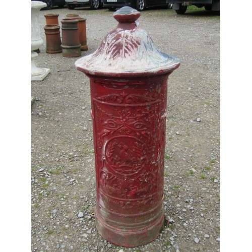 1017 - A painted and weathered cylindrical cast metal post box with raised relief detail beneath a fixed do... 