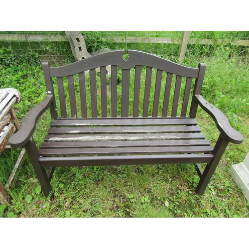 1036 - A stained and weathered teak two seat garden bench with slatted seat and back beneath a broken arche... 