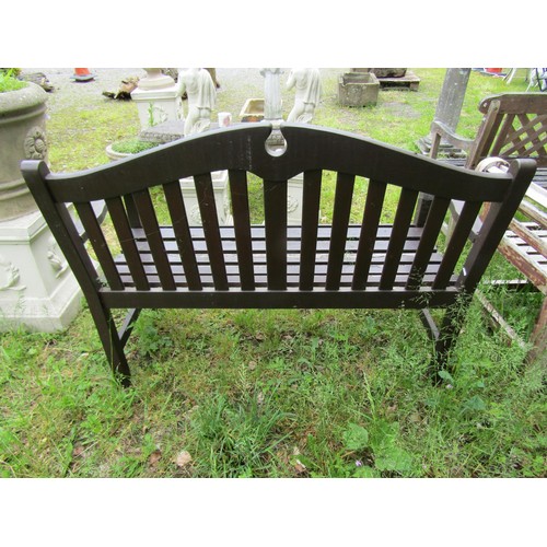 1036 - A stained and weathered teak two seat garden bench with slatted seat and back beneath a broken arche... 