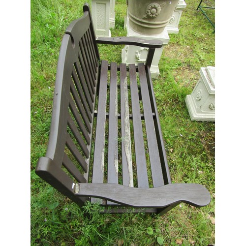 1036 - A stained and weathered teak two seat garden bench with slatted seat and back beneath a broken arche... 