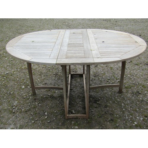 1040 - A weathered Gloucester teak oval drop leaf gateleg garden table with slatted panelled top, 72 cm hig... 